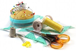 Sewing stuff - pincusion, thimble, thread, scissors, quilting square, and quilting pins, isolated on white.